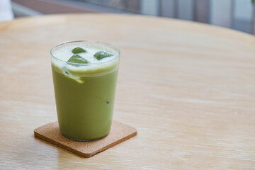 freshness vivid green iced milk matcha  on wood table with green ornamental plant in cafe