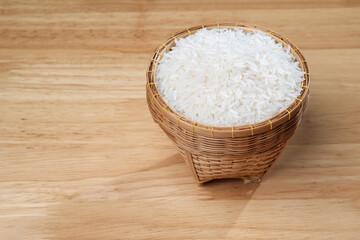 raw Thai's jasmine rice in Thai's traditional style bamboo's bowl on wooden dinner table