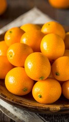 A wooden bowl overflows with bright, shiny, small citrus fruits