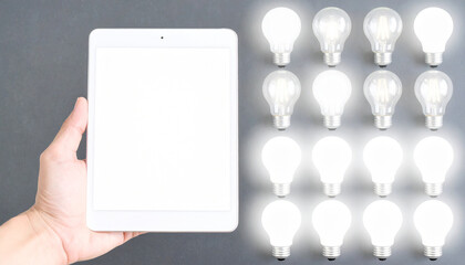 Obraz premium Hand holding tablet with glowing lightbulbs technology