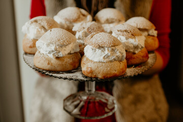 Traditional cream buns with powdered sugar on glass cake stand