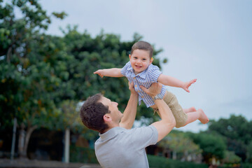 Father and young toddler son walk and play in the sand on the beach in Bali, Indonesia