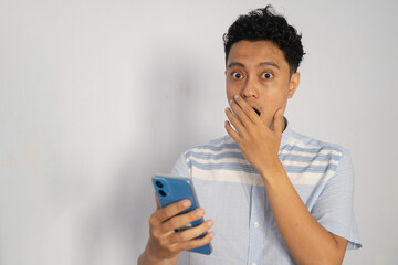 Astonished Young Man Expressing Surprise While Looking at His Smartphone in Shocked Reaction