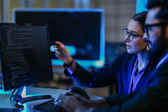 diverse AI developers collaborate in a late-night coding session. A senior engineer mentors his colleague as they program a complex machine learning algorithm together. - Powered by Adobe