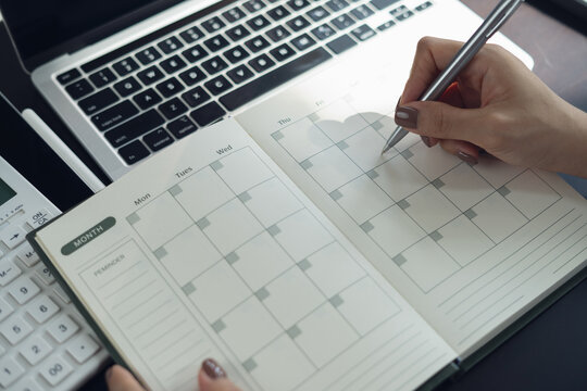 Closeup, woman hand writing on 2026 calendar event planner to set timetable organize schedule, event planning for business meeting or vacation plan. business planning concept.