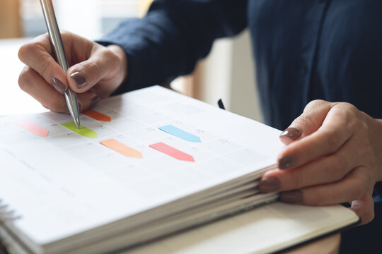 2026 Event planner timetable agenda plan on schedule event. Business woman checking planner, taking note on calendar desk on office table. Calendar event plan, work planning