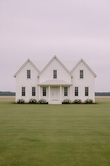 Minimalist White Farmhouse in Open Countryside Under Cloudy Sky
