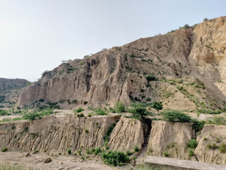 Rocky Hillside with Light-Colored Cliff, Sparse Vegetation, and Clear Blue Sky