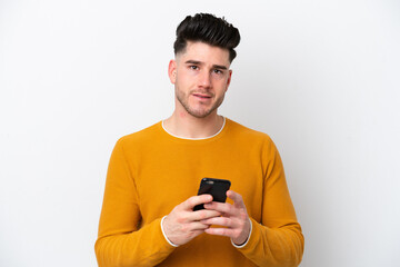 Young caucasian man isolated on white background sending a message with the mobile
