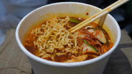 Bowl of Korean ramen noodles in rich red broth, served with kimchi, tofu, and vegetables for a flavorful, spicy comfort meal.