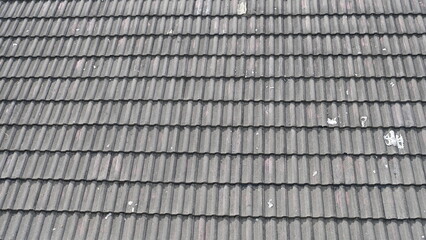 Close-up view of weathered gray concrete roof tiles arranged in uniform rows, showing texture,...