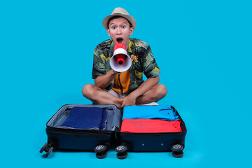 Young Man Sitting Amidst An Open Suitcase, Holding A Megaphone And Screaming