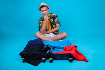 Stressed Traveler Guy Sitting On An Overflowing Suitcase While Putting Hand On Chin