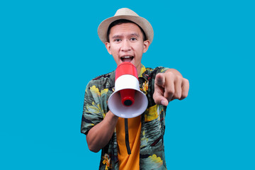 Excited Traveler Asian Man Holding A Megaphone And Pointing Forward Against Blue Background