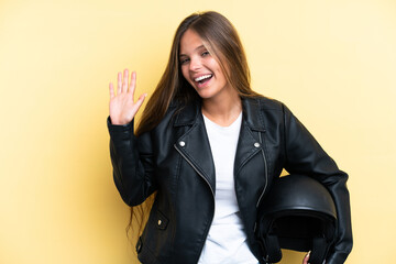 Young caucasian woman with a motorcycle helmet isolated on yellow background saluting with hand with happy expression © luismolinero