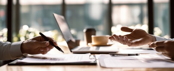 The business meeting at a sunlit desk with laptop, documents and coffee