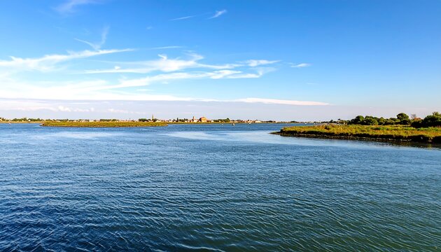A tranquil waterway stretches across a placid body of water, with a low-lying shoreline featuring sparse vegetation and a distant settlement.