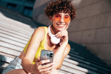 Young beautiful smiling hipster woman in trendy summer clothes. Carefree woman with curls...