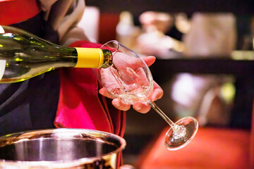 飲食店で、よく冷えた白ワインを注ぐ人