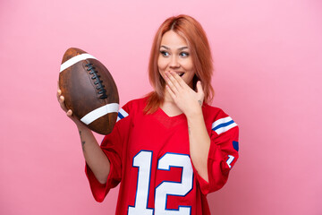 Young Russian girl playing rugby isolated on pink background with surprise and shocked facial...