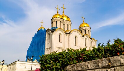 A grand cathedral, adorned with golden domes, stands under a vibrant blue sky.