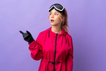 Skier teenager girl with snowboarding glasses over isolated purple background intending to realizes the solution while lifting a finger up