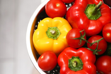 Fresh organic vegetables in bowl. Red tomatoes with stems and colorful peppers closeup. Healthy natural food for cooking. Raw seasonal harvest on kitchen table. Bright vegetables background for diet.
