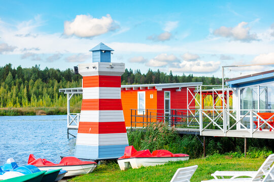 Beautiful wooden red and white lighthouse on the lake shore on a bright sunny day - Powered by Adobe
