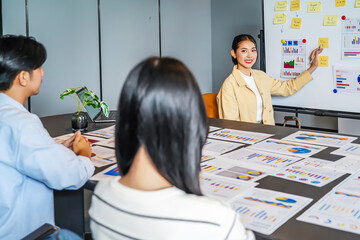 In a vibrant corporate setting, a dynamic young asian businesswoman presents important statistical...