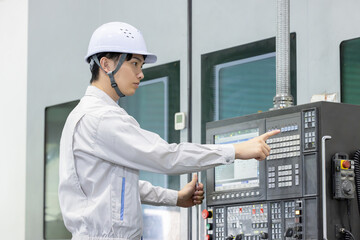 工場の操作盤の前で働く男性作業員