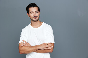 Smiling man with crossed arms looking confidently at the camera, dressed in a casual white t-shirt,...