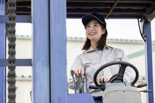 倉庫でフォークリフトを運転する若い女性