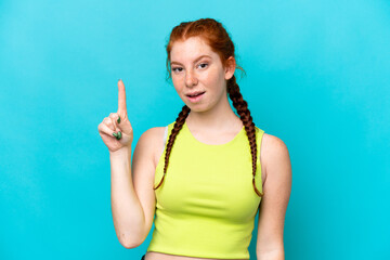 Young reddish woman isolated on blue background intending to realizes the solution while lifting a...