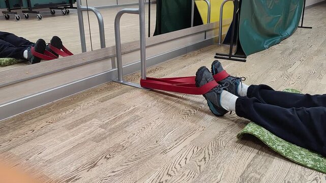 Engaging in a leg exercise with a resistance band inside of a gym environment.