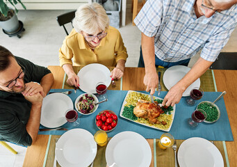 Happy multi-generation family gathering around dining table and having fun during a lunch or dinner...