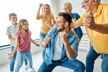 Portrait of a three generation famili, grandparents, parents and children playing and having fun dancing at home