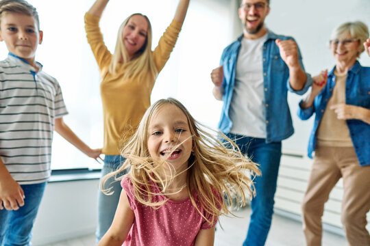 Portrait of a three generation famili, grandparents, parents and children playing and having fun dancing at home