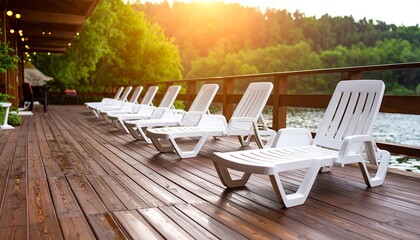 Sun-drenched wooden deck with rows of white lounge chairs overlooking a serene lake.