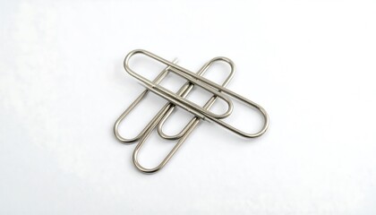 Fototapeta premium Three metal paperclips arranged on a white surface.