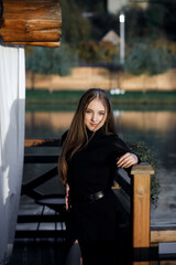 A woman stands on a wooden bridge near a picturesque pond. She leans on the railing.