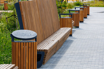 There is a high wooden bench next to the path in the park