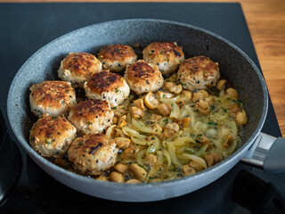 Frying pork meatballs with white mushrooms and onion in frying pan