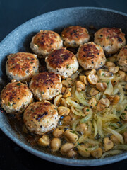 Frying pork meatballs with white mushrooms and onion in frying pan