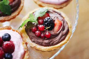 Sweet tartlet with chocolate cream and fresh berries. Closeup of dessert with blackberry, raspberry...