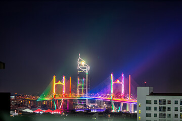 Blurred background of night lights in Bangkok. Fireworks, traffic lights, lights on bridges over the river, the spread of electric lighting technology in homes.