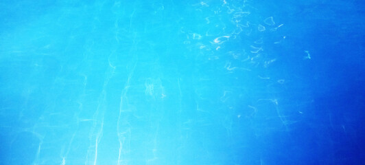 The crystal clear turquoise blue pool water surface gently ripples, reflecting sunlight and...