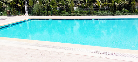 The crystal clear turquoise blue pool water surface gently ripples, reflecting sunlight and...