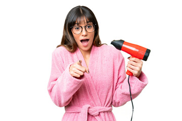 Young caucasian man holding a hairdryer over isolated chroma key background surprised and pointing...