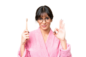 Young caucasian woman holding a toothbrush over isolated chroma key background showing ok sign with fingers