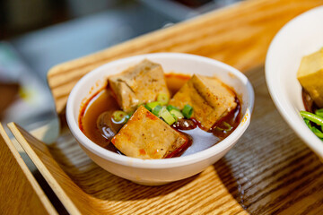 Side view of Taiwanese hot pot noodle soup with wide noodles, cabbage, baby corn, tofu puffs, and pork slices in a clear savory broth